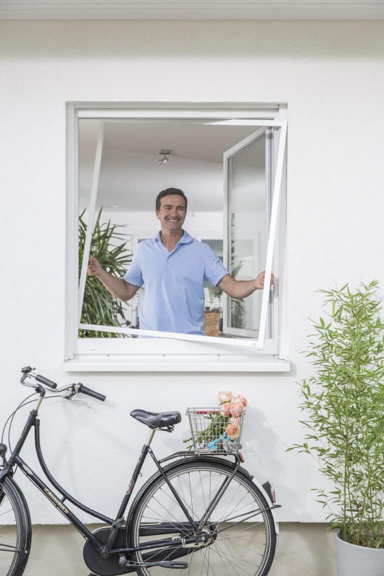 Maßgefertigter Fliegengitter-Spannrahmen in Heidelberg an einem Fenster mit Mann im Außenbereich und Fahrrad davor