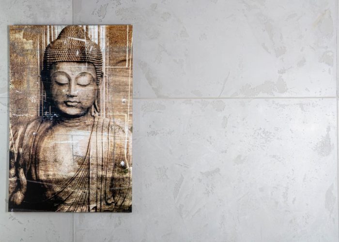 Moderner Wohnstil mit einer effektvollen, hellgrauen Wandbeschichtung im Beton-Look und einem Leinwandgemälde des Buddha in Braun-Tönen.